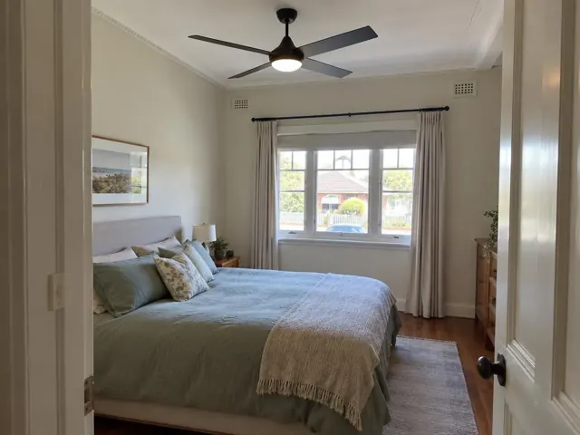 Bedroom with a modern ceiling fan, bed, window and curtains in a suburban home in Georgetown