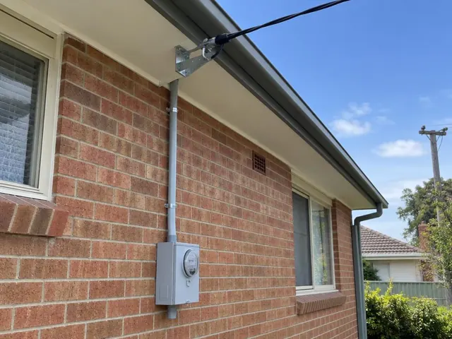 Brick house exterior with new overhead service cable and point-of-attachment bracket in Mayfield